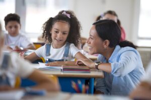 Leerkracht stelt coachende vragen aan leerling tijdens lesmoment, met focus op eigenaarschap en leren.