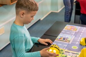 Leerling in de onderbouw oefent programmeren met een beebot, werkend aan basisvaardigheden in digitale geletterdheid en ict.