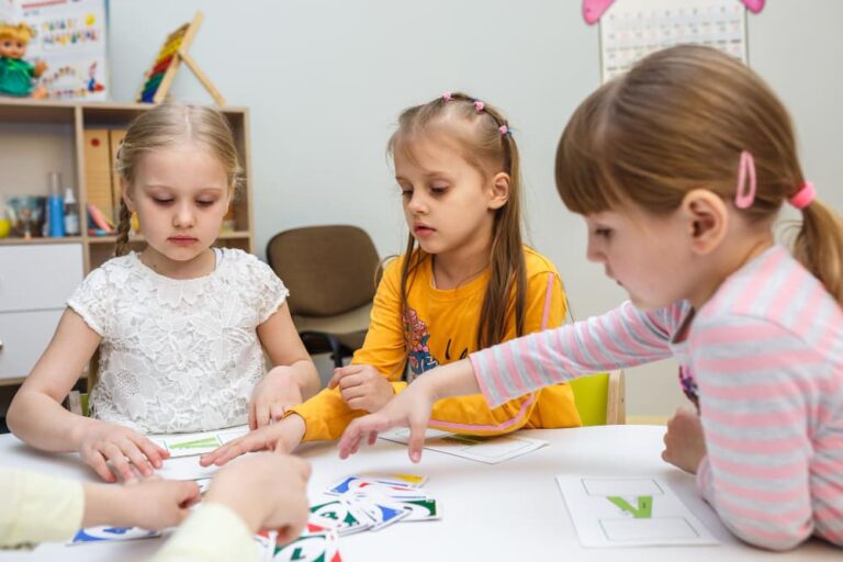 Kleuters zijn bezig met een lesactiviteit aan een tafel, werkend aan een doorgaande lijn naar groep 3.