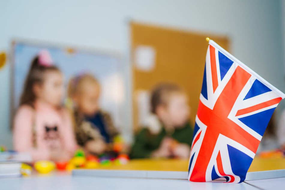 Engelse vlag in een klaslokaal op de voorgrond, leerlingen die een les volgen op de achtergrond.