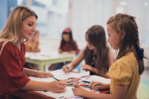 Leerkracht en pedagogisch coach in gesprek en werkend met kinderen in de klas.