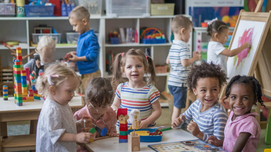 Kinderen spelen in een kleuterlokaal met een rijke speelleeromgeving ingericht.