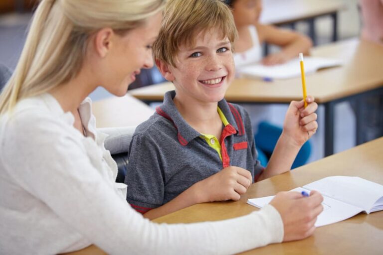 Leerkracht en leerling werken samen, in positieve interactie, in de klas.