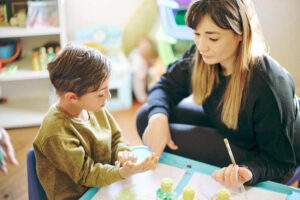 Begeleider werkt met leerling aan een tafel middels HGB aan passend en inclusief onderwijs.