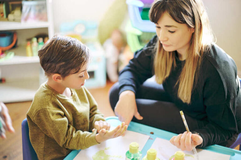 Begeleider werkt met leerling aan een tafel middels HGB aan passend en inclusief onderwijs.