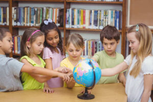 Kinderen uit unit-groep met elkaar in bibliotheek, werkend aan opdracht wereldoriëntatie.