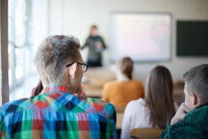 Schoolleider doet een flitsbezoek in een klas tijdens een les, observeert achterin.