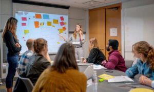 Adviseur begeleidt een schoolteam bij een ontwikkeltraject, met post-its op het bord en gezamenlijke focus op schoolontwikkeling.