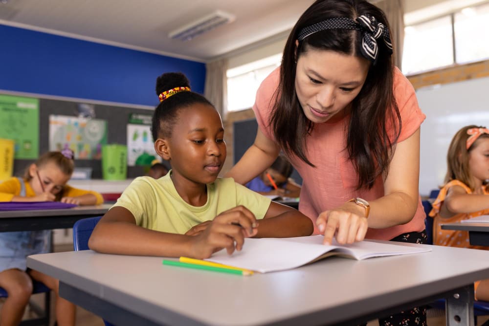 Juf helpt leerling bij een taalopdracht in de klas.